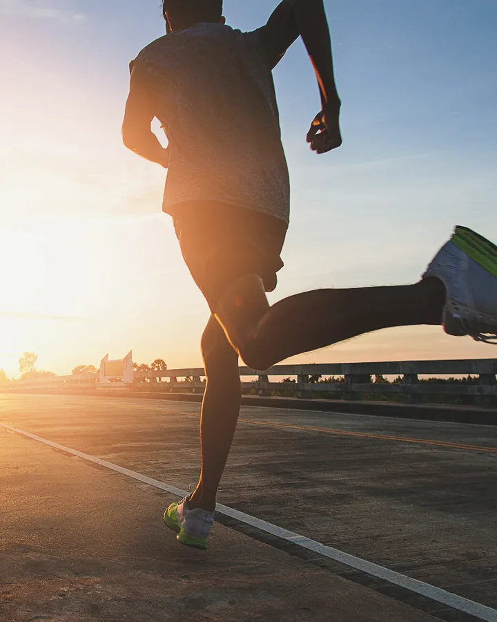 A runner on a road bridge at sunrise.
